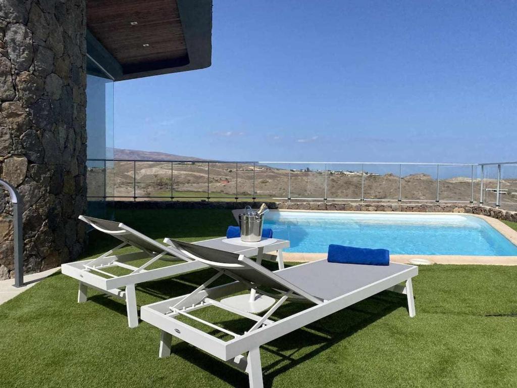 eine Terrasse mit einem Tisch und Stühlen neben einem Pool in der Unterkunft Villa Calm Ocean views by Infinity Summer in La Playa de Arguineguín
