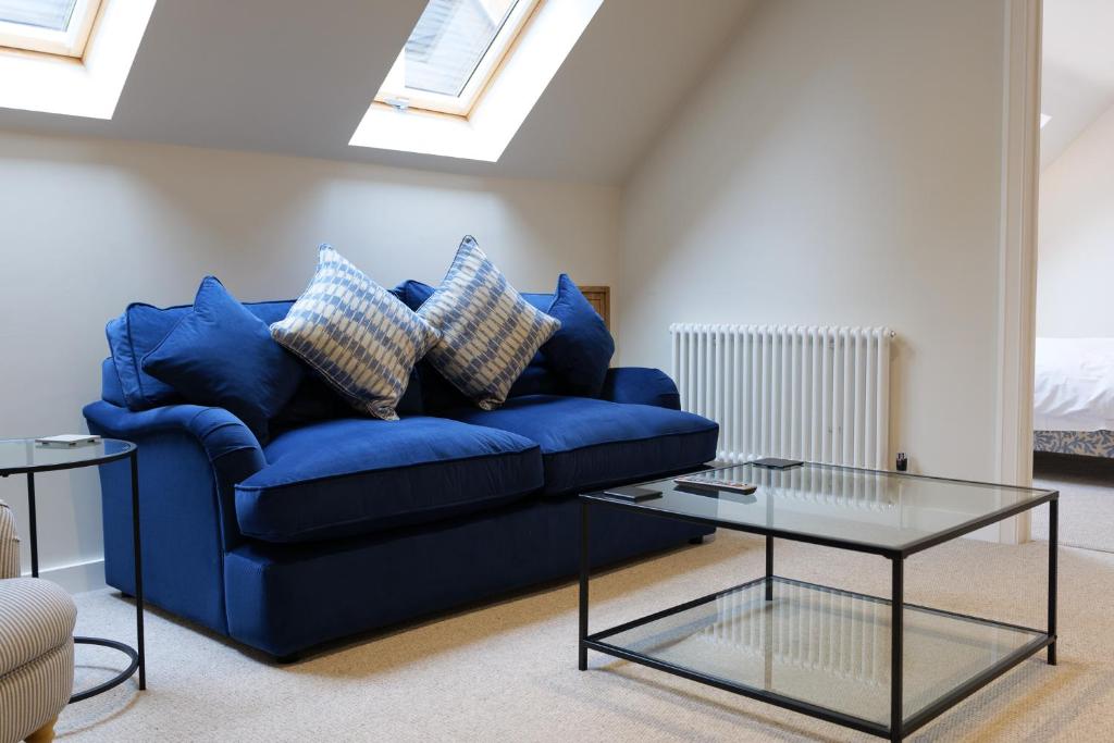 a blue couch in a living room with a glass table at The Willow Apartment - Greentrees Estate in Haywards Heath