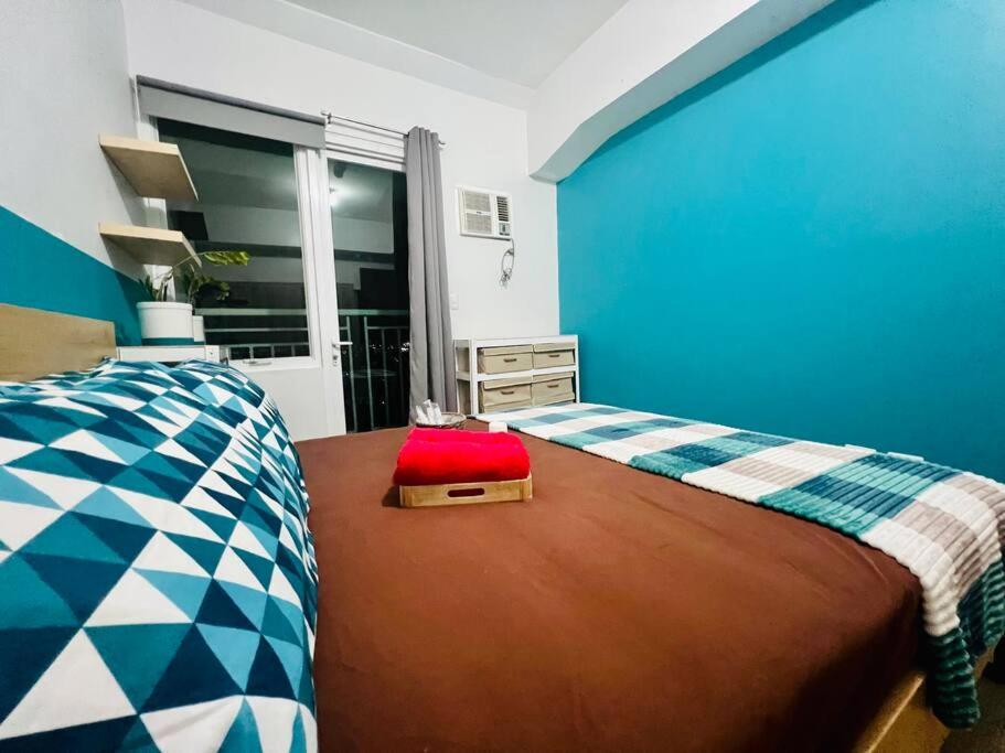 ein blaues Schlafzimmer mit einem Bett mit einem Koffer drauf in der Unterkunft Cozy Place Anuva Residences in Manila
