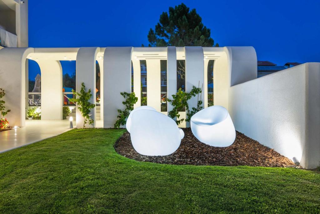 two white chairs sitting on a lawn in front of a building at Cocoοns Suites & Villas Fourka in Fourka