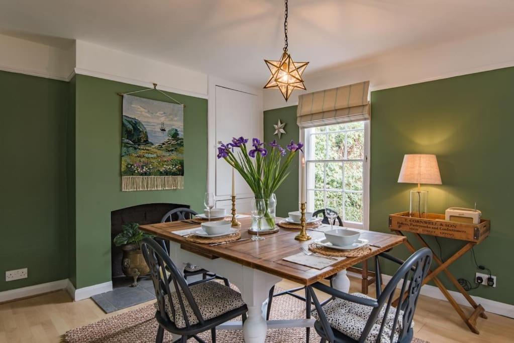 uma sala de jantar com paredes verdes e uma mesa de madeira com cadeiras em Cliffeside Cottage em Kingsdown