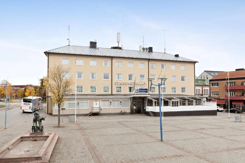 um grande edifício com um autocarro estacionado em frente em Best Western Vetlanda Stadshotell em Vetlanda