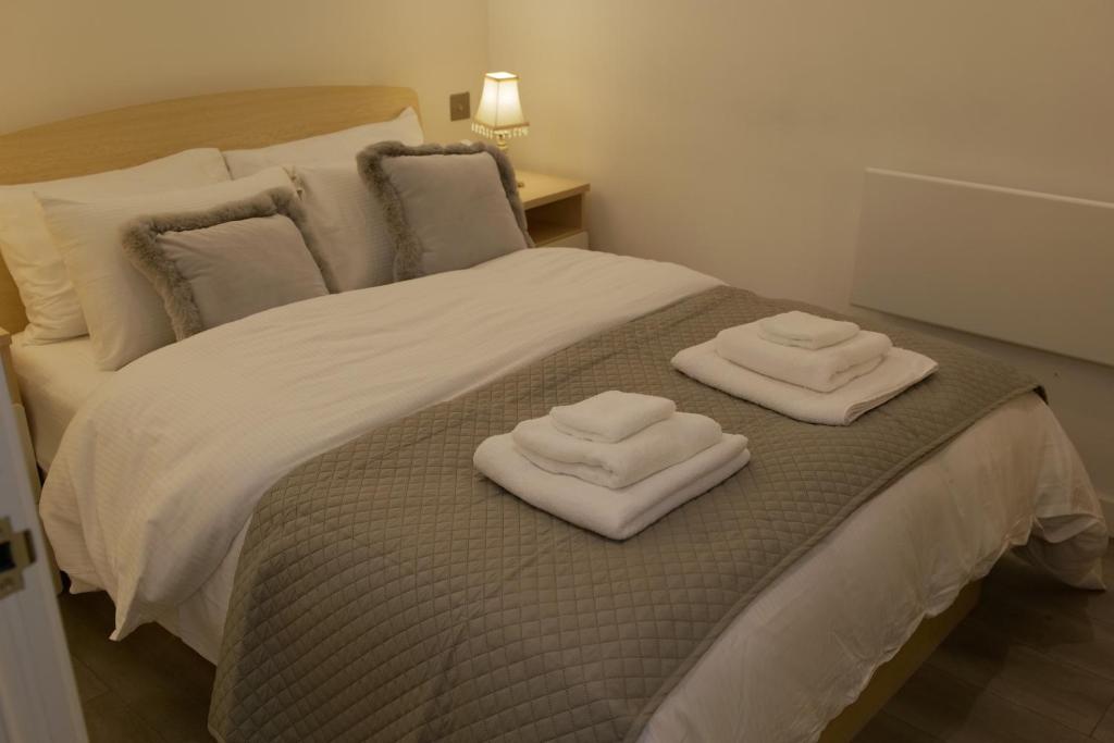 a bed with two folded towels on top of it at Luxurious Short Stay Flat in Milton Keynes in Milton Keynes