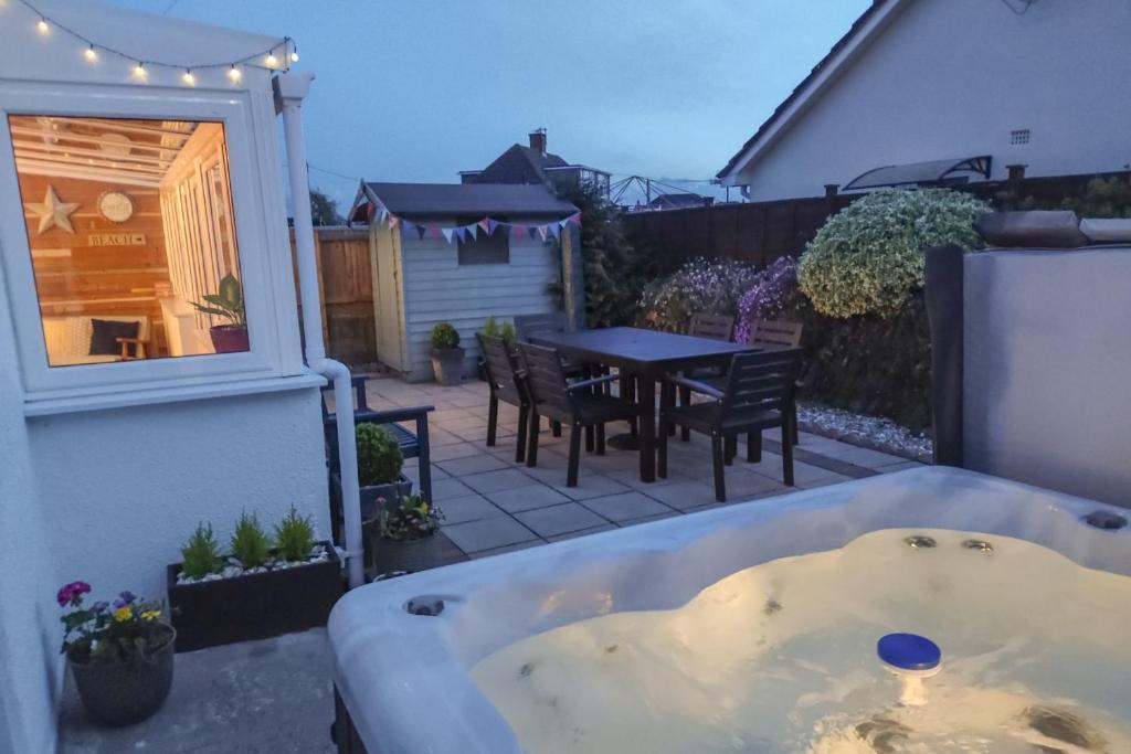 - un bain à remous sur une terrasse avec une table et des chaises dans l'établissement BRAUNTON BEACON VIEW 3 Bedrooms, à Braunton