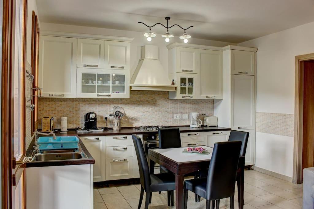 eine Küche mit weißen Schränken und einem Tisch und Stühlen in der Unterkunft Casa Cornelia in Lucolena in Chianti