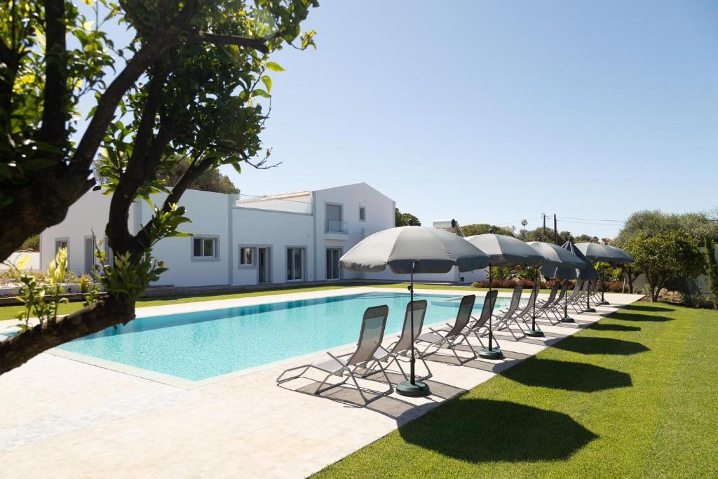 a row of chairs and umbrellas next to a swimming pool at O PINHAL DO AVÔ in Almancil