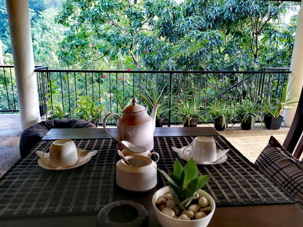 Tantra Ella Lodge في إيلا: طاولة مع غلاية الشاي وأكواب على شرفة