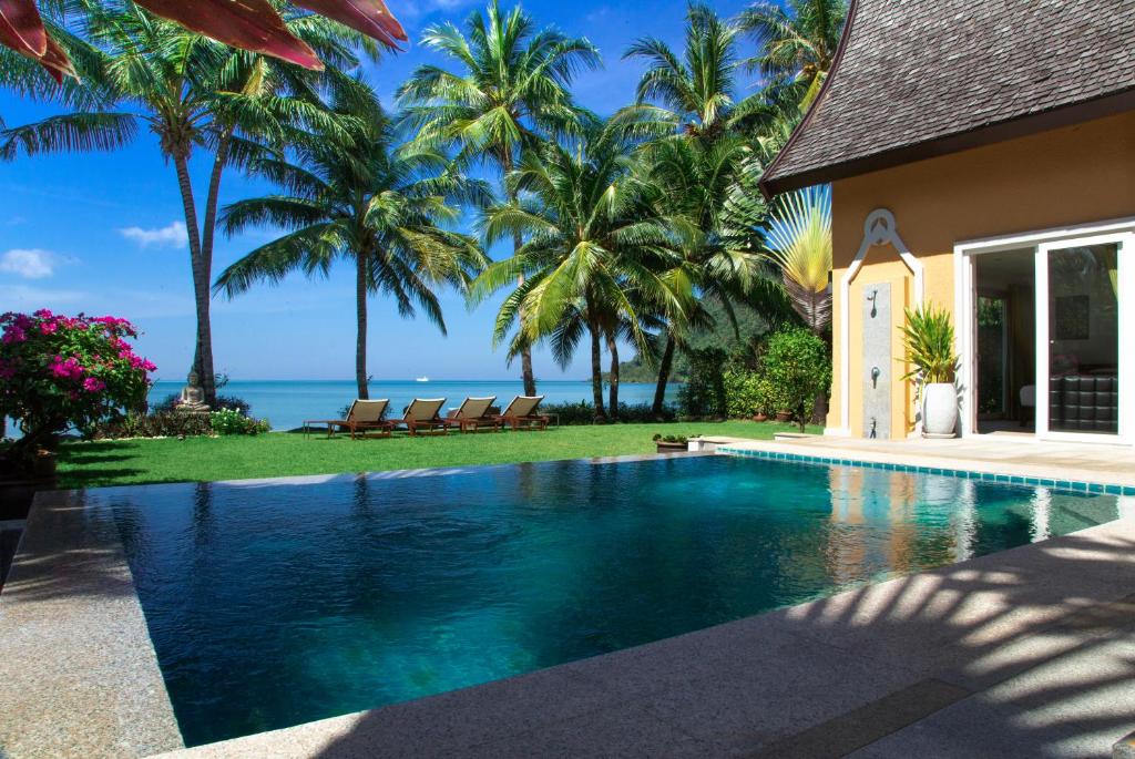 een zwembad voor een huis met palmbomen bij Beachfront 5-bedroom Villa in Ko Chang