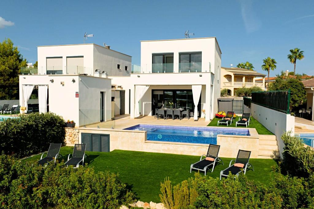 uma casa branca com piscina e cadeiras em Villa Corb Mari II em Playa de Muro