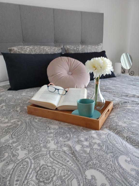 a tray with glasses and a book on a bed at La Plaza Apartamento Armilla in Armilla