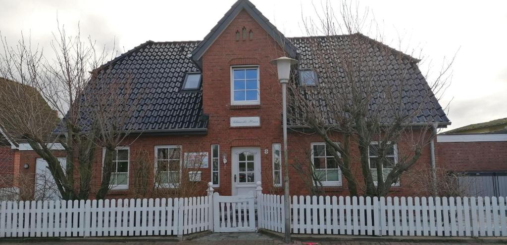 a red brick house with a white fence at Schmucke-Huus-Bungalow in Westerland (Sylt)