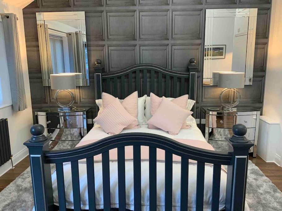 Schlafzimmer mit einem Bett mit rosa Kissen und Spiegeln in der Unterkunft Open plan Stylish Apartment in rural Kent in Kent