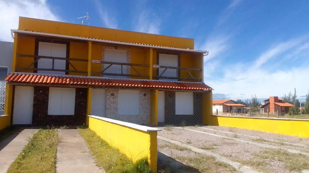 ein gelbes und weißes Gebäude mit blauem Himmel in der Unterkunft Recanto das Pedras - CASA Pedra Portuguesa - Com vista para o mar in Jaguaruna