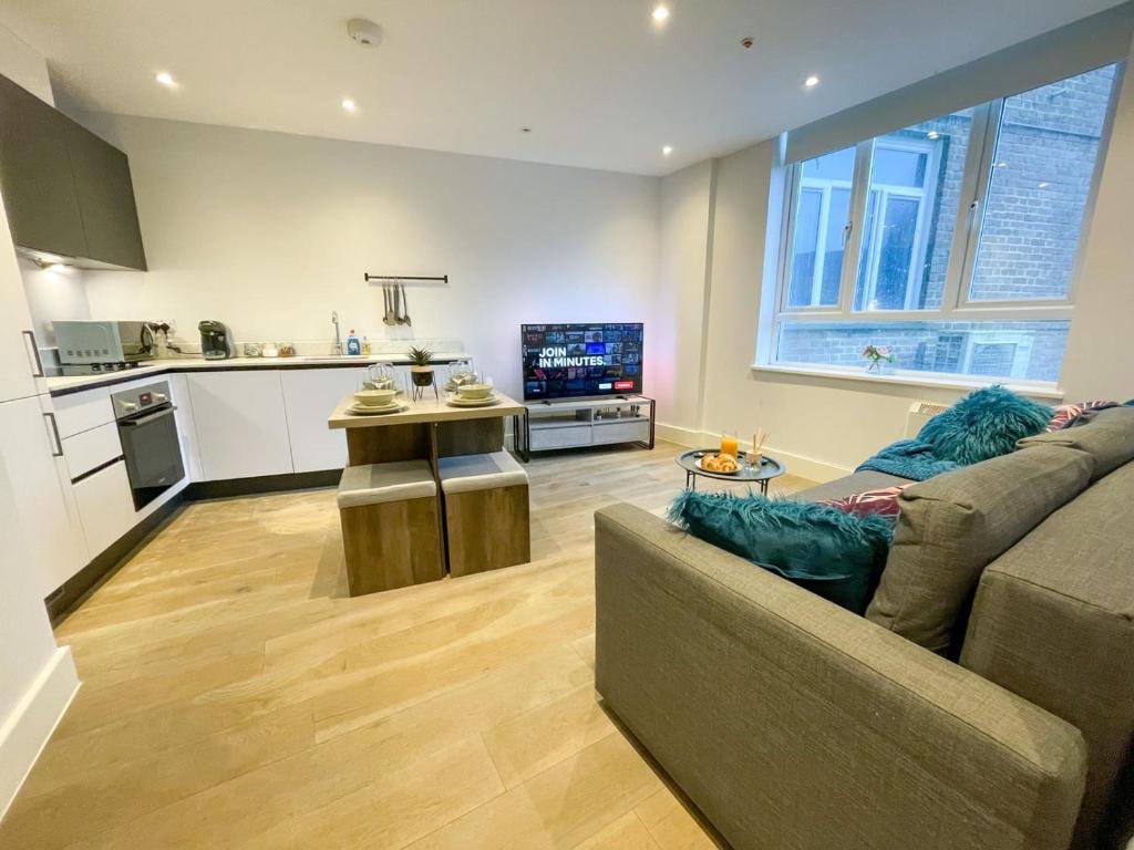 Super Cosy Apartment in The Heart Of Chelmsford في تشيلمسفورد: غرفة معيشة مع أريكة ومطبخ