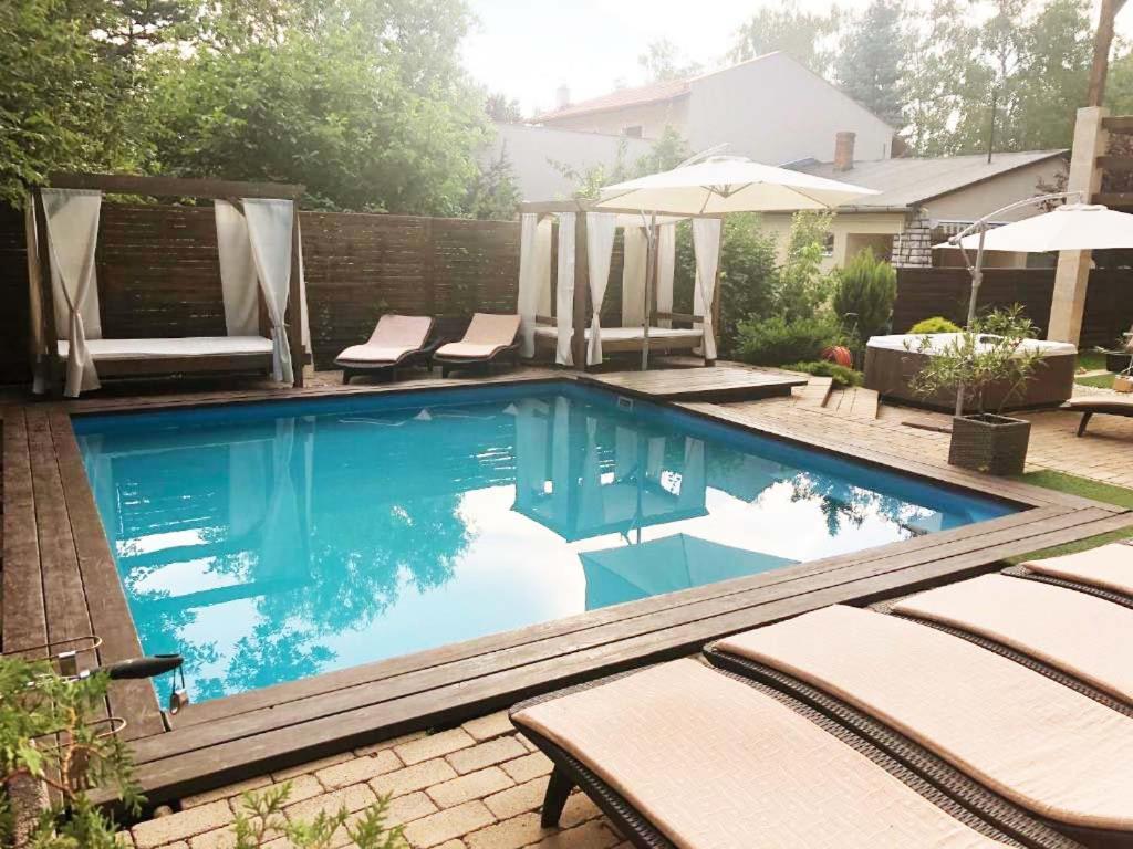 uma piscina num quintal com cadeiras e um guarda-sol em Silver Garden em Siófok