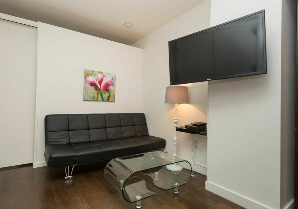 sala de estar con sofá de cuero negro y TV de pantalla plana en 2BD 1BA Apartment At Financial District, en Nueva York