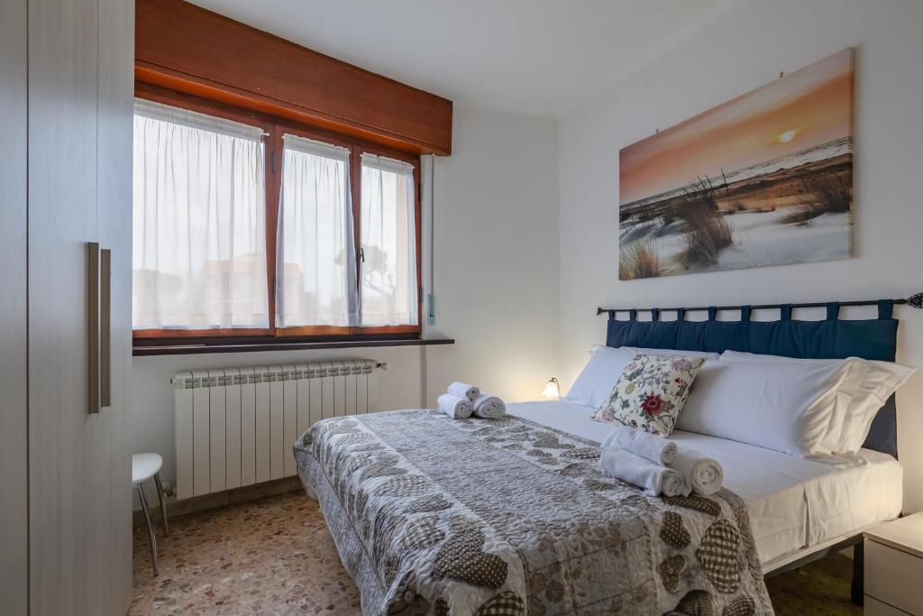 a bedroom with a bed and two windows at Tirrenia Cozy Apartment near the Beach in Tirrenia