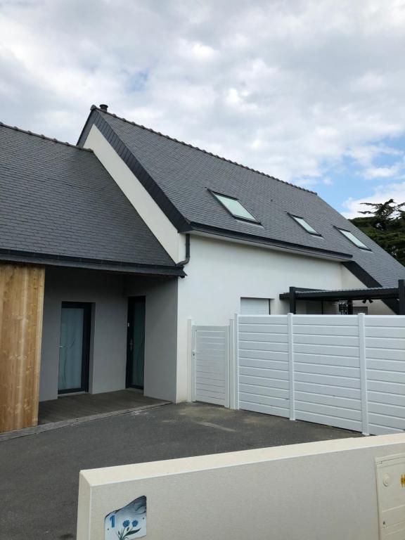 une maison blanche avec une clôture et un toit dans l'établissement Les Bleuets, à Erdeven