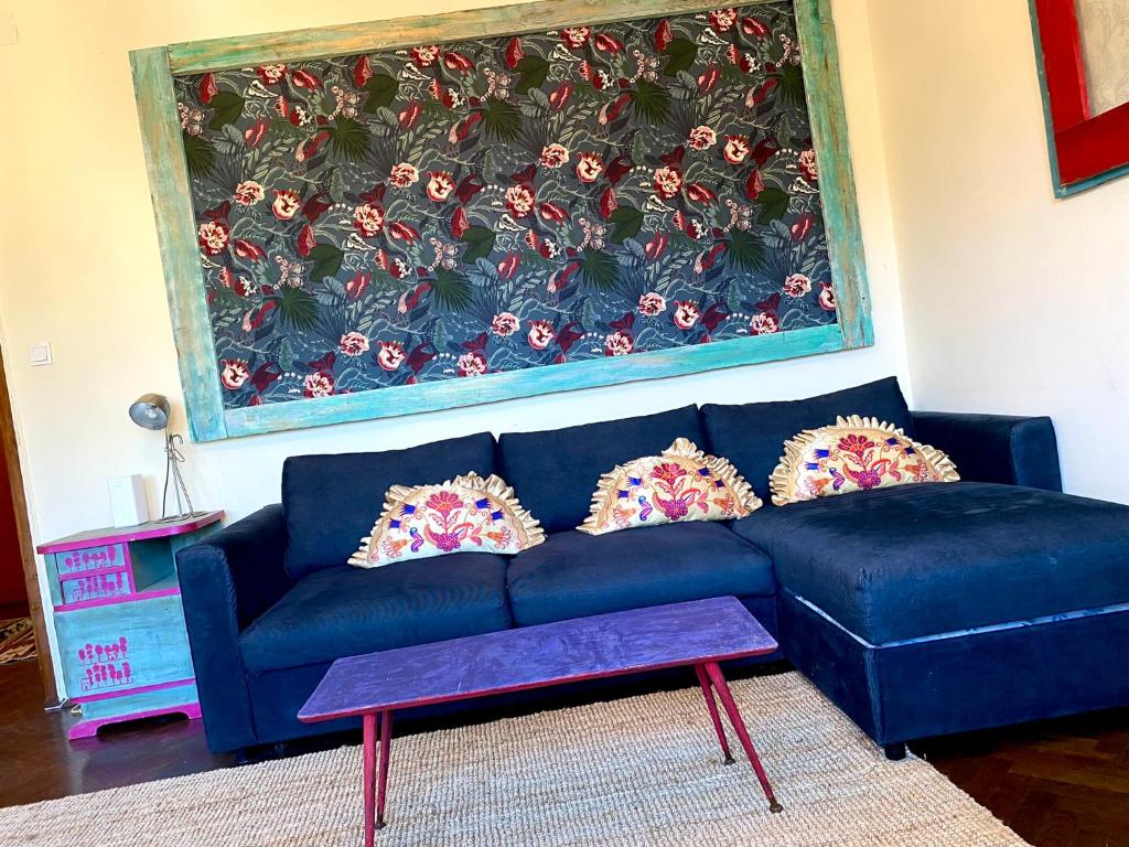 a blue couch in a living room with a large painting at Lovely cosy art flat in Budapest