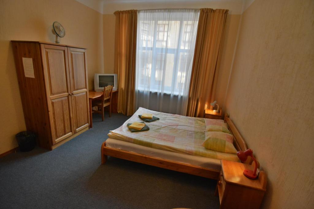a bedroom with a bed and a desk and a window at Hotel Multilux with Self Check-in in Riga