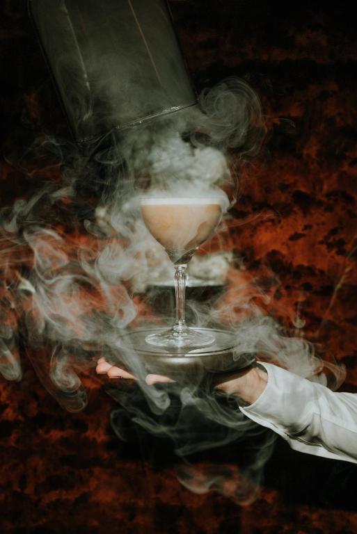 a person holding a glass with smoke around it at Hôtel La Sivolière in Courchevel