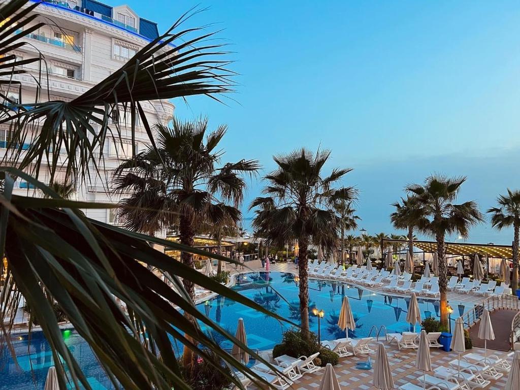 a resort with a large swimming pool with chairs and palm trees at The Wish House in Golem