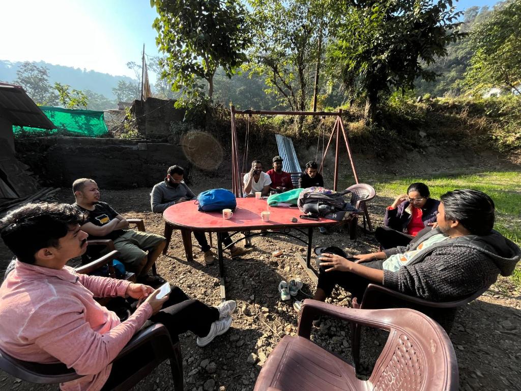 een groep mensen die rond een picknicktafel zitten bij Joey's Hostel Rishikesh in Rishīkesh