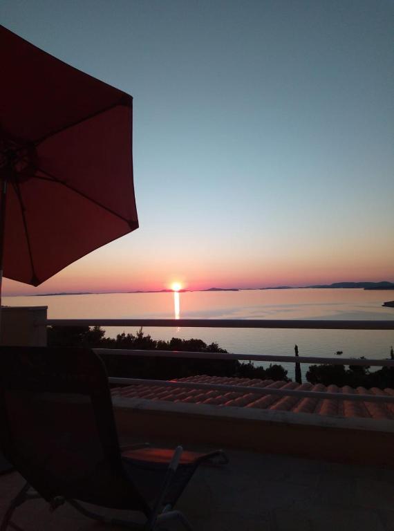 a sunset over the ocean with a chair and an umbrella at Sunny P in Primošten