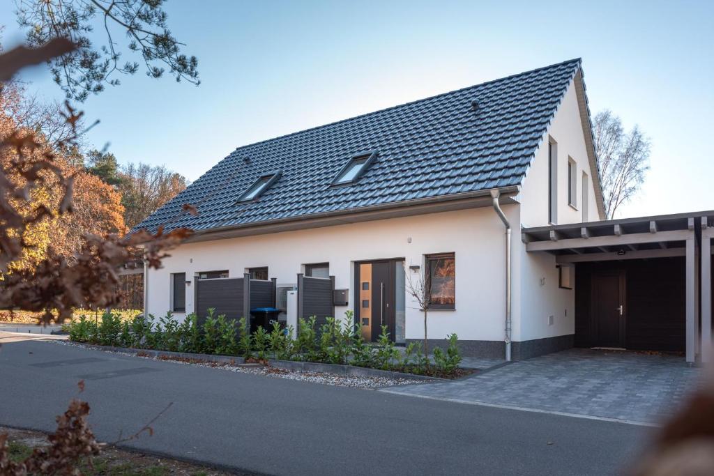 a white house with a black roof and a driveway at Ferienhaus Ulrichshorst in Ulrichshorst