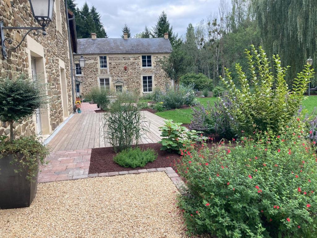 un jardín frente a una casa de piedra con flores en Le Coteau du Seigneur, 