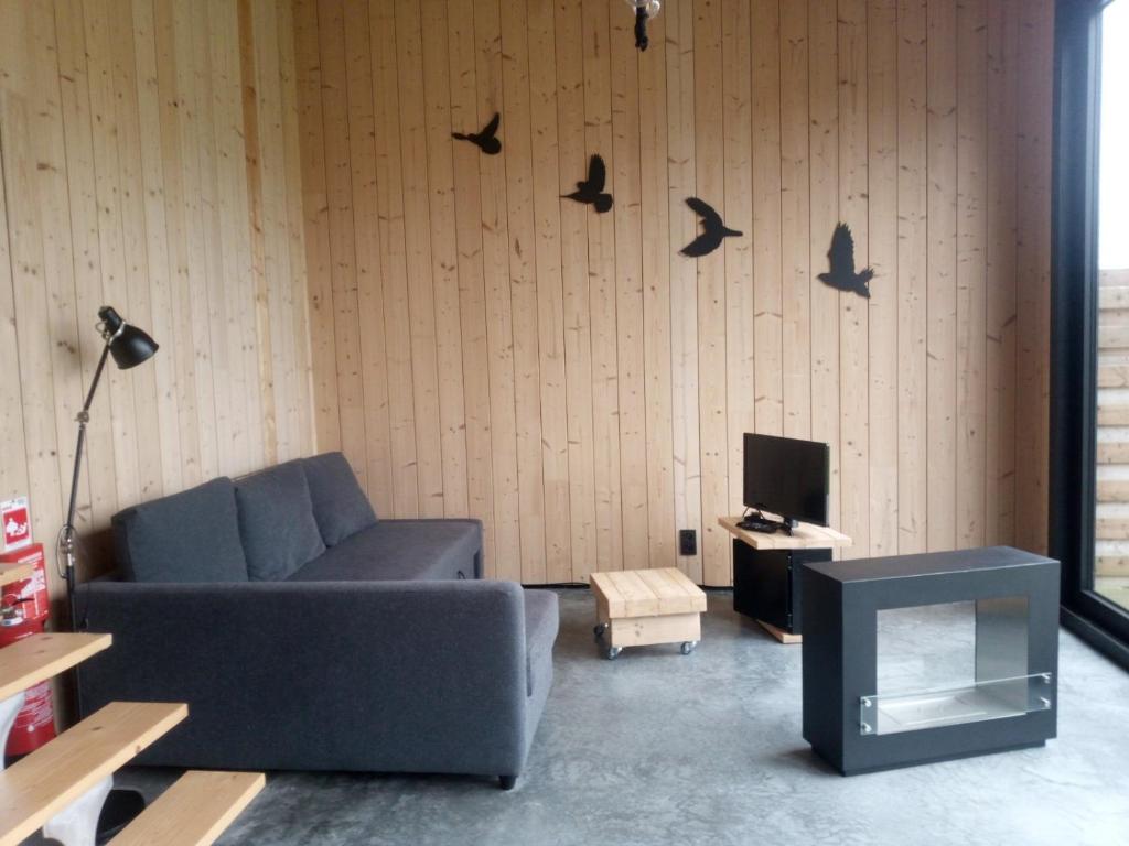 ein Wohnzimmer mit Sofa und Vögeln an der Wand in der Unterkunft Station 25A in Duffel