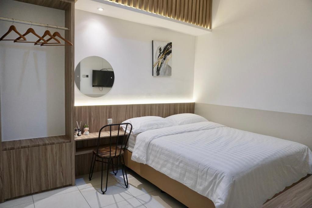 1 dormitorio con cama, escritorio y espejo en Aurora House Surabaya, en Wijung