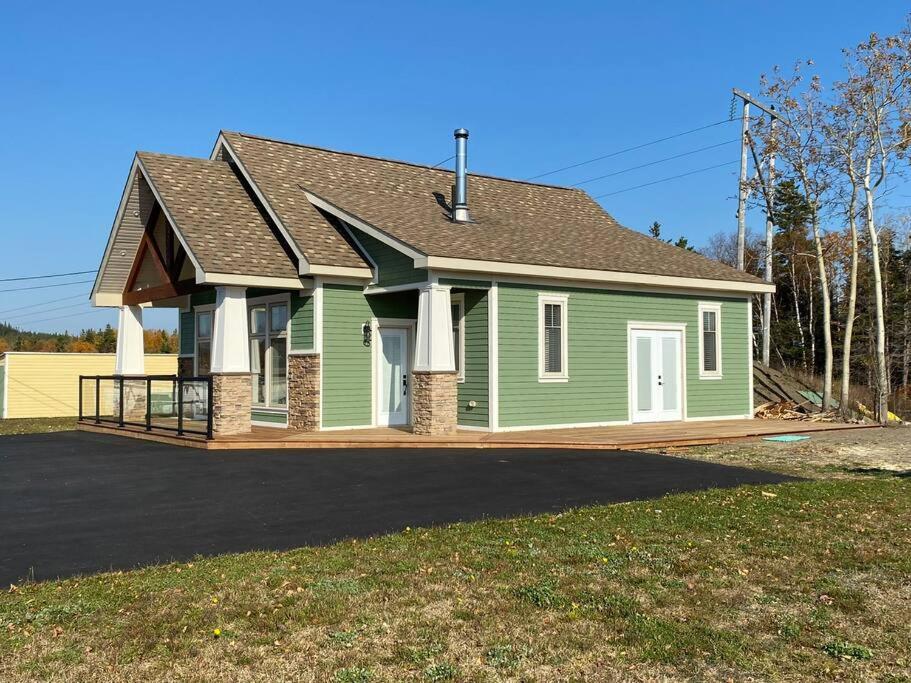 uma casa verde com um telhado numa entrada em The Millhouse Oceanfront Cottage 