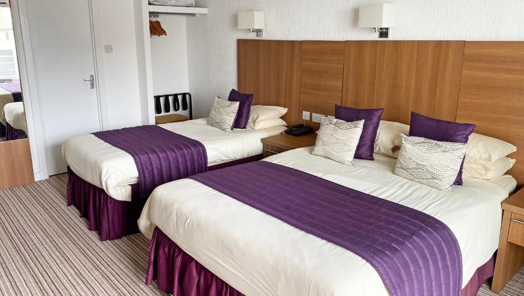 ein Hotelzimmer mit 2 Betten mit lila Bettwäsche in der Unterkunft Magnuson Hotel Sandy Lodge Newquay in Newquay