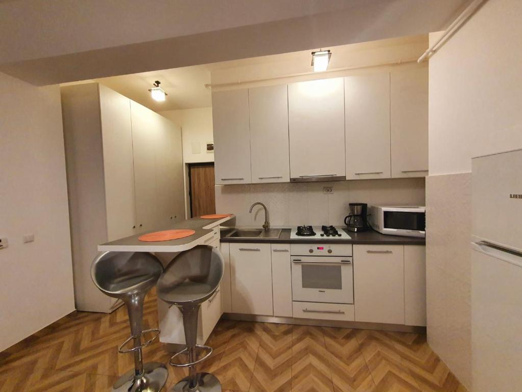 a kitchen with white cabinets and a table and stools at Concept Residence Regim Hotelier in Iaşi