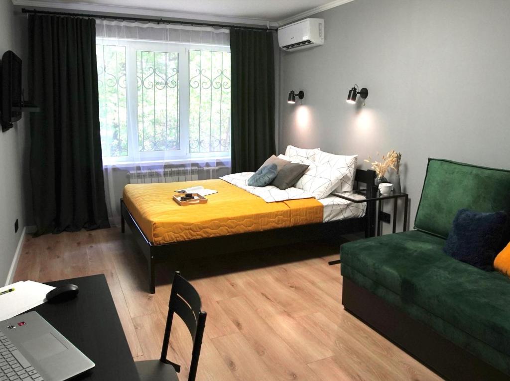 a bedroom with a bed and a green couch at Almaty Aparts in Almaty