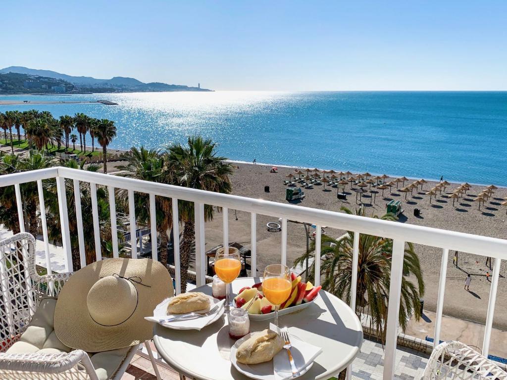 - une table avec de la nourriture et des boissons sur un balcon donnant sur la plage dans l'établissement Miradores Malagueta Beach, à Malaga