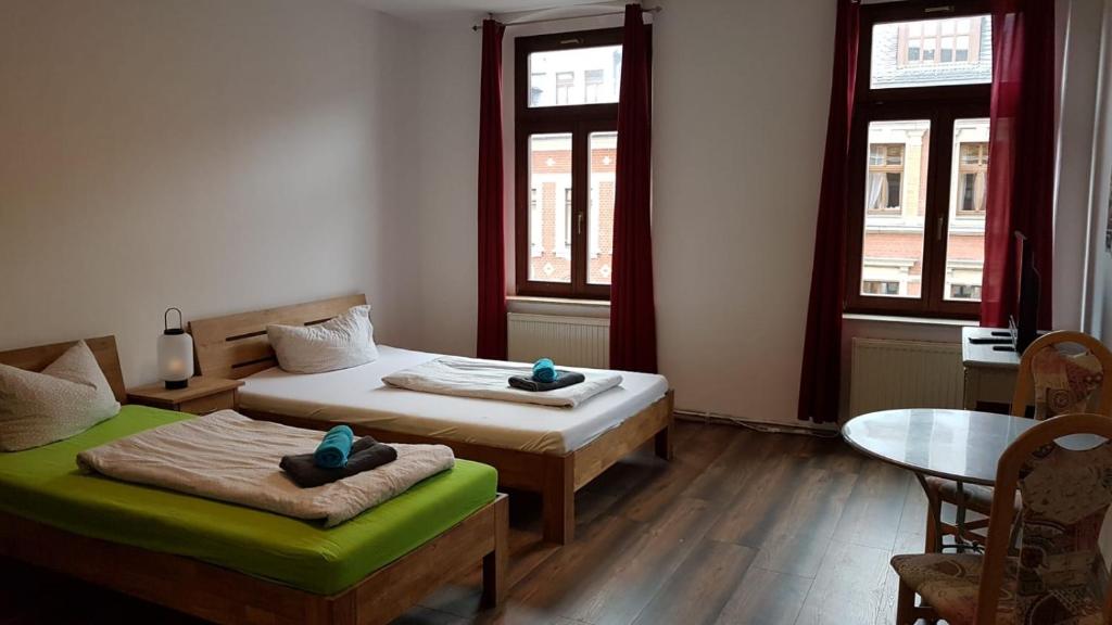 a room with two beds and a table and two windows at Phoenix in Chemnitz