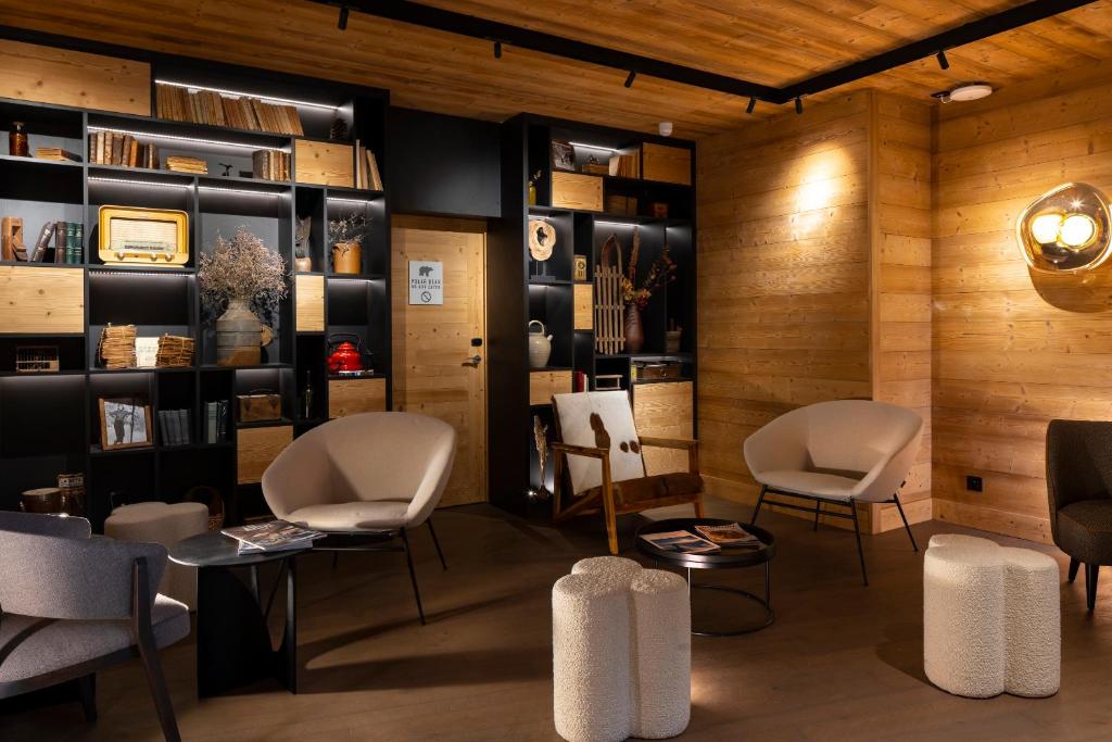 a waiting room with chairs and bookshelves at HIGALIK HOTEL in Les Menuires