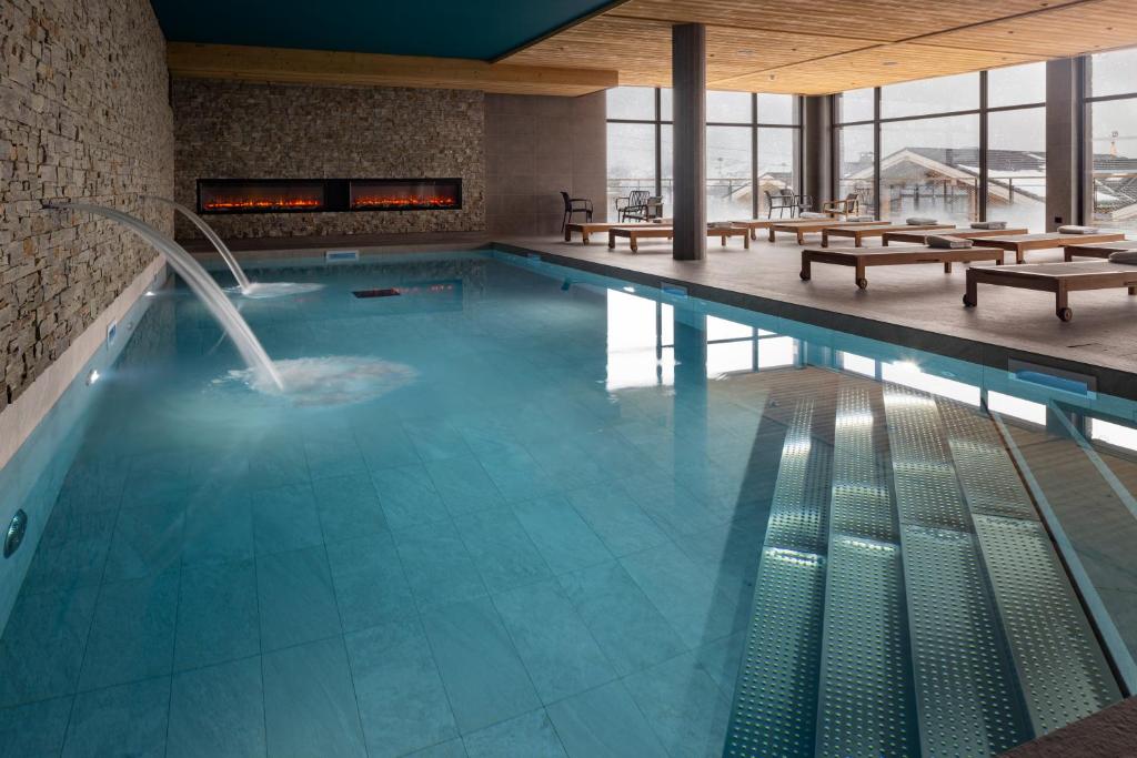 a swimming pool with a fountain in a building at HIGALIK HOTEL in Les Menuires