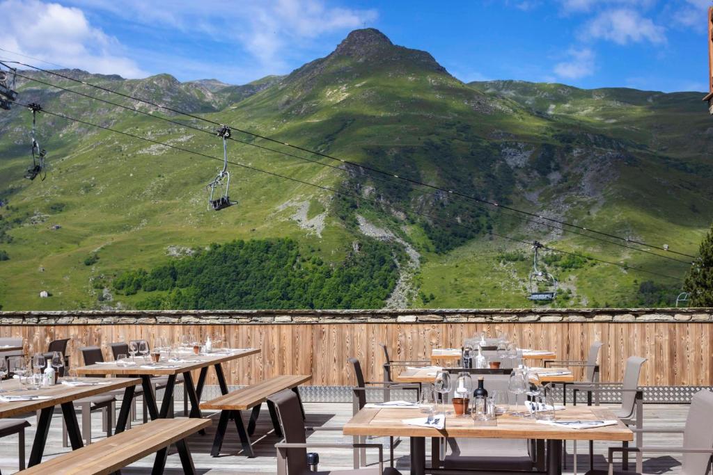 a restaurant with tables and a mountain in the background at HIGALIK HOTEL in Les Menuires