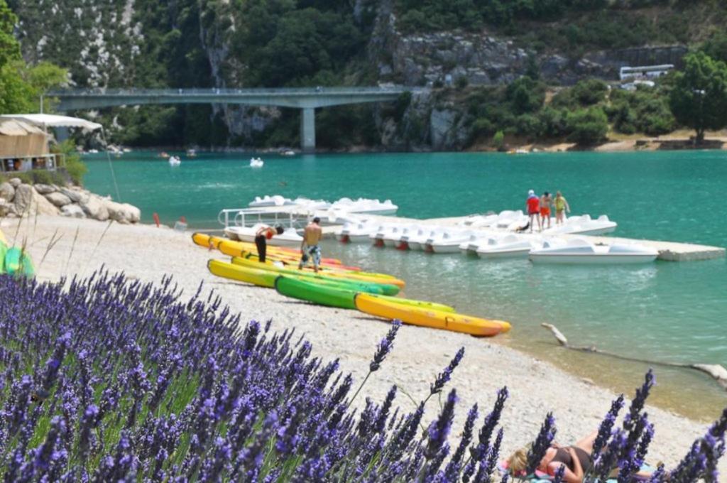 un groupe de bateaux dans l'eau avec des gens sur une plage dans l'établissement BUNGALOW / CAMPING 3* / GORGES DU VERDON / PROCHE DU LAC DE STE CROIX /STANDING/ 4 P, à Sainte-Croix-de-Verdon