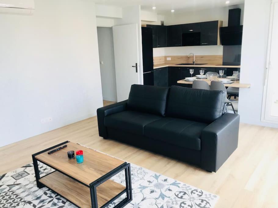 un salon avec un canapé noir et une table dans l'établissement Appartement Haut de gamme Créteil, à Créteil