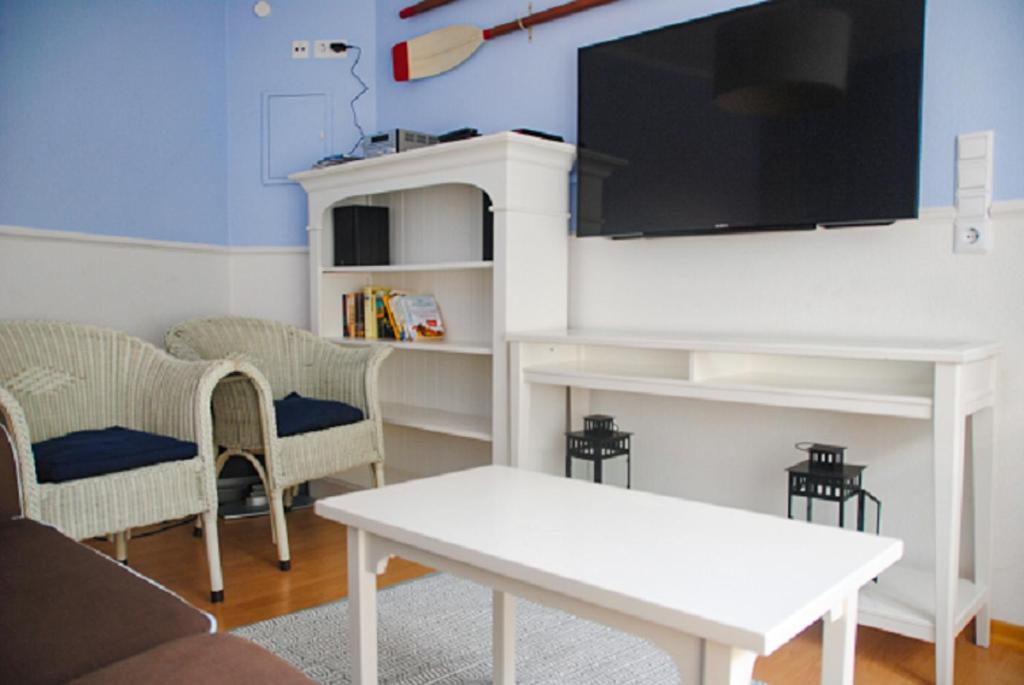 ein Wohnzimmer mit einem weißen Tisch und einem Flachbild-TV in der Unterkunft Groot Huus in Norderney