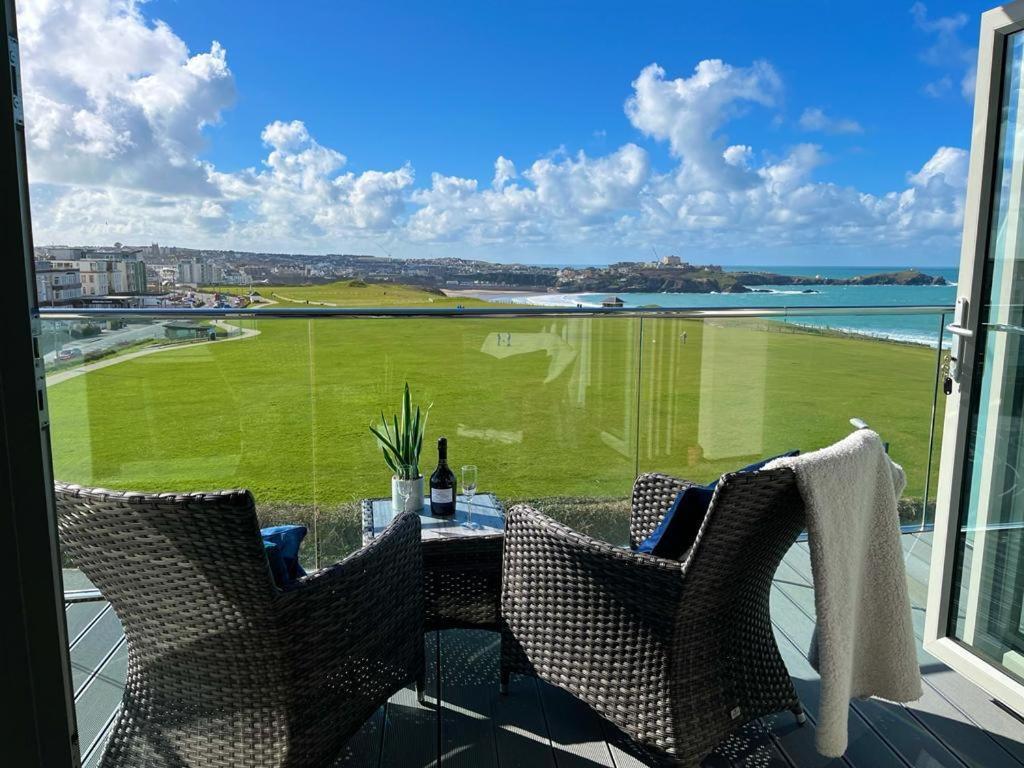 a balcony with a table and chairs and a view of a golf course at Lowen in Newquay
