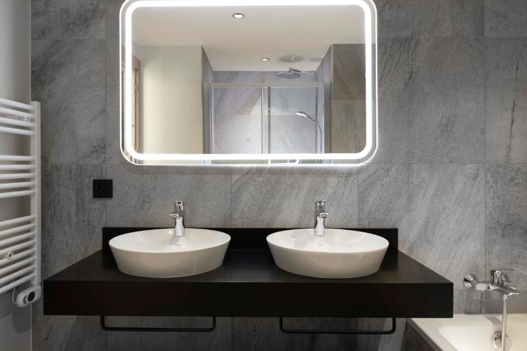 a bathroom with two sinks and a mirror at HIGALIK HOTEL in Les Menuires