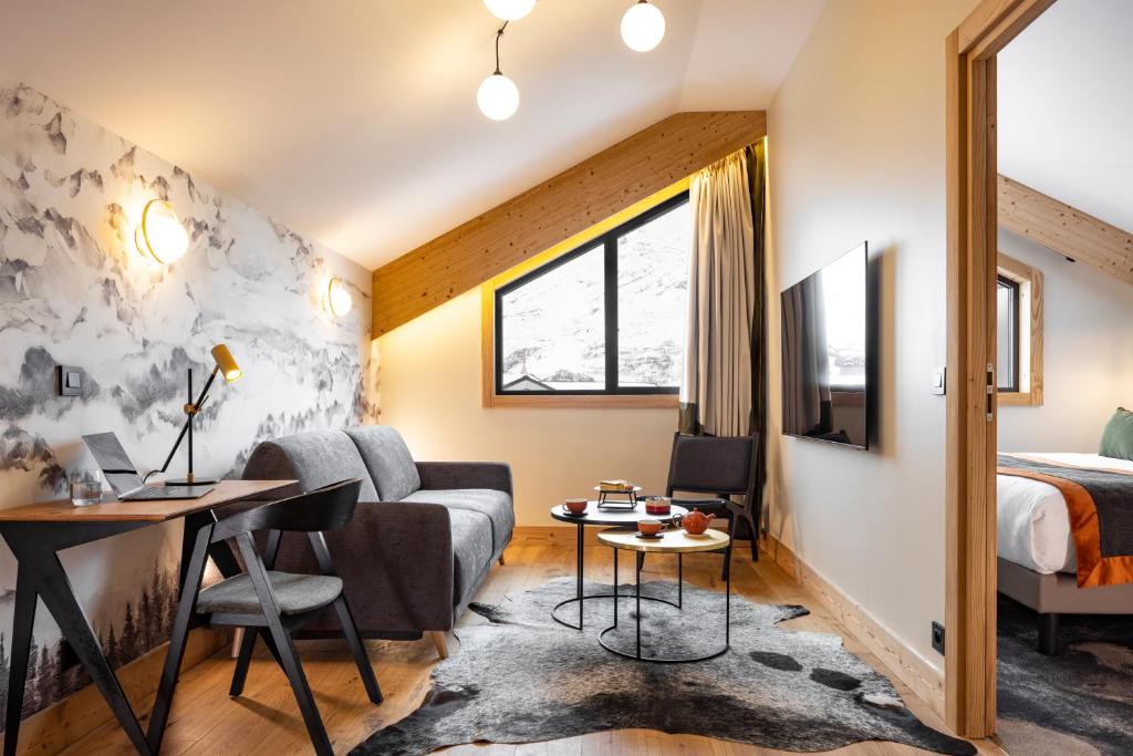 a room with a bed and a couch and a table at HIGALIK HOTEL in Les Menuires