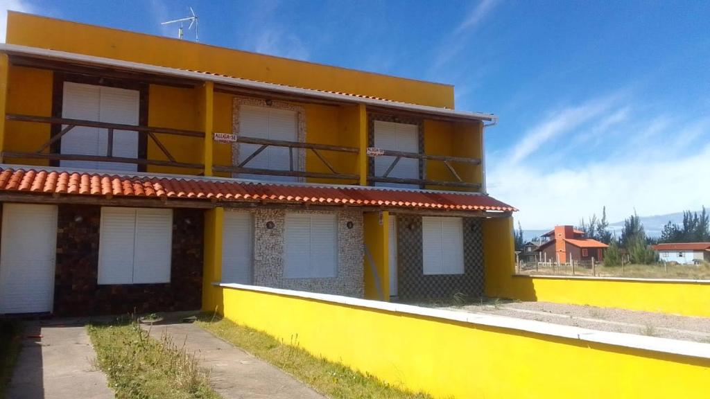 un bâtiment jaune et blanc avec un mur jaune dans l'établissement Recanto das Pedras- Casa Pedra Ardósia - Com vista para o mar, à Jaguaruna