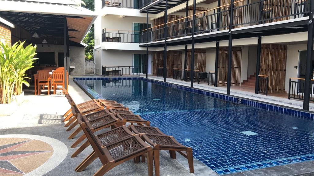 2 sedie a sdraio sedute accanto alla piscina di Celosia Chiang Mai Hotel a Chiang Mai