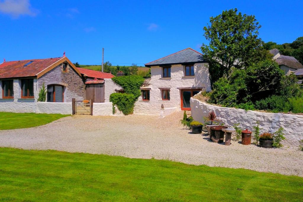 a house with a stone wall and a yard at SAUNTON SUNSHINE COTTAGE 3 Bedrooms in Braunton